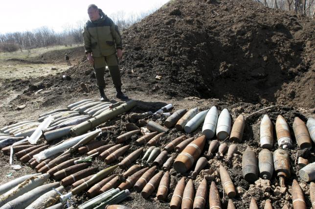 A pro-Russian rebel stands near Ukrainian military unexploded shells at a range in the suburbs of Donetsk